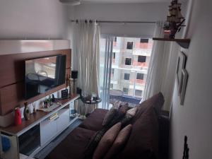 ein Wohnzimmer mit einem Sofa und einem TV in der Unterkunft Residencial Innovare 1 in Praia Grande