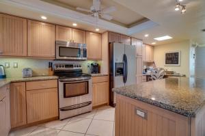 a kitchen with wooden cabinets and stainless steel appliances at Spectacular Sunsets at this Beachfront Condo in Bradenton Beach