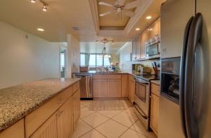 a kitchen with wooden cabinets and a black refrigerator at Spectacular Sunsets at this Beachfront Condo in Bradenton Beach