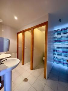 a bathroom with a sink and a toilet and a mirror at Albergue Valle de Arbas in Cubillas de Arbas