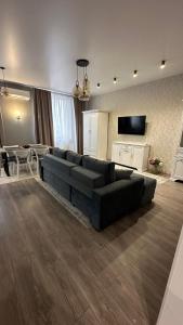 a living room with a black couch and a kitchen at Apartment in center of Chisinau in Chişinău