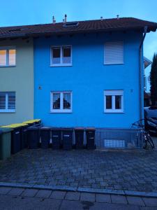 a blue house with trash cans in front of it at FeWo BlackForest in Neuenburg am Rhein