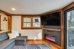a living room with a couch and a tv and a fireplace at Waterfront Duluth Cabin with Deck and River View! in Duluth