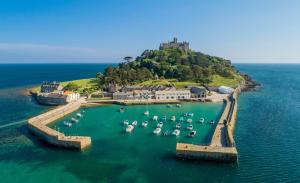 an island with boats in the water with a castle at Large newly refurbished modern house, part sea views, south facing garden, parking in Penzance