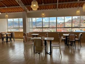 a restaurant with tables and chairs and large windows at INYAWASI APARTMENT in Cusco
