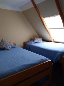 two beds in a small room with a window at Cabaña Elu in Llico