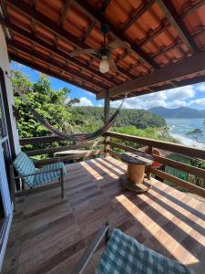 a porch with chairs and a hammock and a view of the ocean at Mirante do Pirata Suítes Bed and Breakfast in Ubatuba