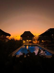 um pôr-do-sol sobre uma piscina num resort em Kite Eco House em Salina de Rey