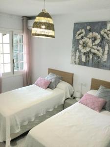 a room with three beds and a hanging light at Apartamento Playa Xoriguer con piscina y jardin in Son Xoriguer