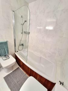 a white bathroom with a shower and a toilet at Apartamento Playa Xoriguer con piscina y jardin in Son Xoriguer