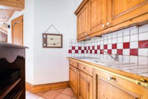 uma cozinha com um lavatório e um relógio na parede em Résidence La Ginabelle - maeva Home - Appartement 4 Pièces 8 Personnes - Séle 65 em Chamonix-Mont-Blanc