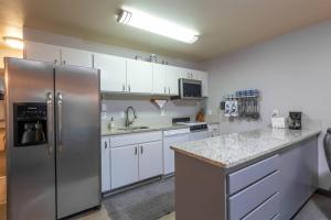 a kitchen with white cabinets and a stainless steel refrigerator at Riverside Condo located Downtown Enjoy Nightlife in Bend +16 photos