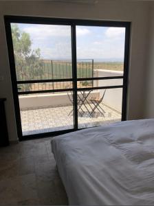1 dormitorio con cama y vistas a un balcón en בית נופש בגלבוע, en Nurit