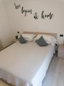 een slaapkamer met een wit bed met een bord dat leest blijf thuis bidden bij Appartamento Meridiana in Arco
