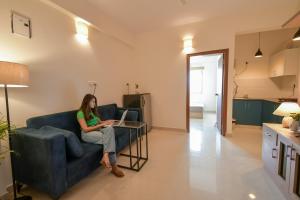 una mujer sentada en un sofá con un portátil en HomeSlice Whitefield - 1BHK/ 2BHK Apartment/ Studio Room en Bangalore