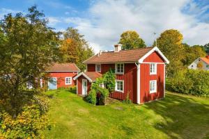 een rood huis op een groene tuin met bomen bij By Lake Rusken - 2 cottages - fantastic nature in Rörvik