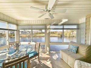 a living room with a ceiling fan and a glass table at Watch the Yachts Waterway Landing Retreat w Pool in Myrtle Beach