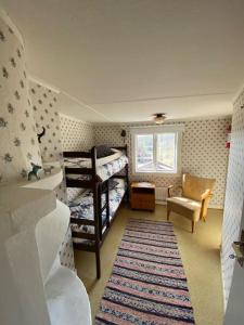 - une chambre avec des lits superposés, une chaise et un tapis dans l'établissement Ekhult Lake Rusken - 2 cottages - fantastic nature, à Rörvik