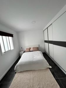 a white bedroom with a large bed and a rug at Casa Daja: uw thuis in Tenerife in Las Lagunas