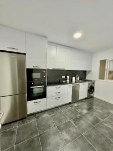 a large kitchen with white cabinets and stainless steel appliances at Casa Daja: uw thuis in Tenerife in Las Lagunas