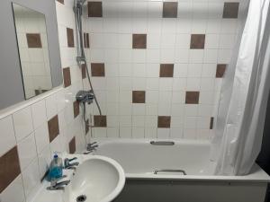 Wembley Serviced Apartment, 20mins from Central London في لندن: حمام مع حوض وحوض استحمام