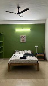 sypialnia z łóżkiem i zieloną ścianą w obiekcie The Last Stop Backpackers Hostel w mieście Auroville