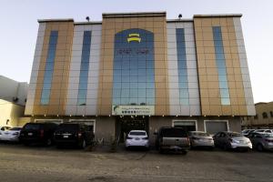 een groot gebouw met auto's geparkeerd op een parkeerplaats bij Rofan house serviced apartments in Riyad