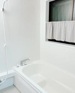 Hita hostel - Vacation STAY 07583v في هيتا: حمام أبيض مع حوض استحمام ومرآة