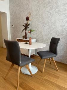 2 Stühle und ein weißer Tisch mit Vase drauf in der Unterkunft Central Apartment 10 in Wien