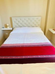 1 dormitorio con cama blanca y manta roja en depto 82, en Cañuelas