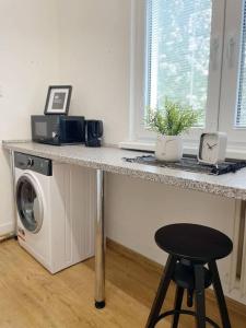 a kitchen counter with a washing machine and a stool at Útulný byt blízko centra Košíc in Košice