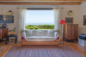 a living room with a couch and a large window at B&B Calata Di Soli in Miniera dellʼArgentiera