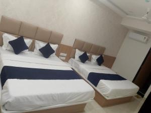 two beds with blue and white pillows in a room at Hotel Bhavya Palace in Anand