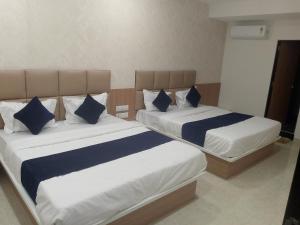 two beds with blue and white pillows in a room at Hotel Bhavya Palace in Anand