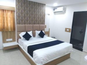 a bedroom with a large white bed with blue pillows at Hotel Bhavya Palace in Anand