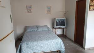 um pequeno quarto com uma cama e uma televisão em Canelo departamento em Ushuaia