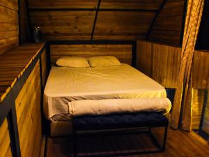 Ce petit lit se trouve dans un dortoir doté de murs en bois. dans l'établissement Omghat Glamping - Cabaña Shiva, à El Peñol