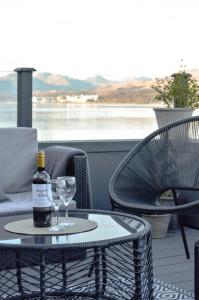 Una botella de vino y dos copas en una mesa. en Lochside cottage with scenic terrace views, Argyll, en Clynder