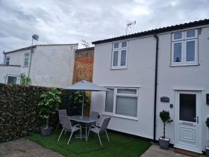 eine Terrasse mit einem Tisch und Stühlen vor einem weißen Haus in der Unterkunft Rugby Coach House, Central location, 5 star rating in Rugby