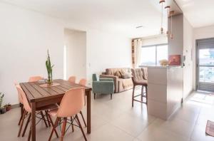 cocina y sala de estar con mesa de madera y sillas en Quarto+banheiro+Wi-Fi frente Floripa Shopping, en Florianópolis