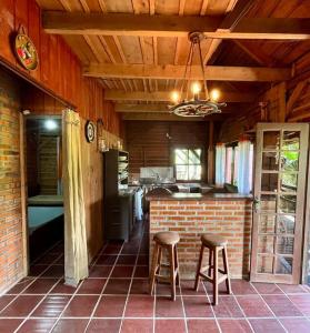 eine Küche mit zwei Hockern und einer Ziegelwand in der Unterkunft Chalé canadense em Rio Bonito in Rio dos Cedros