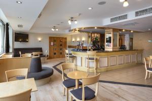 um restaurante com um bar e mesas e cadeiras em London - Wembley International Hotel em Londres