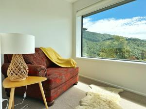 a living room with a red couch and a window at Picton Hilltop Apartment in Picton