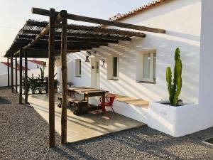 ein weißes Haus mit einem Tisch und einem Kaktus in der Unterkunft Casa Nascente - Casas de Seixe in Baiana