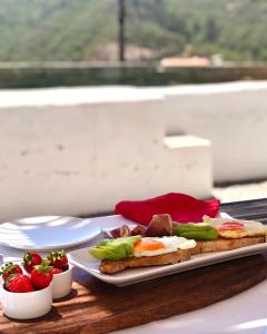 ein Tisch mit zwei Tellern mit Essen und Erdbeeren darauf in der Unterkunft Casa Nascente - Casas de Seixe in Baiana
