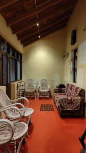 uma sala de estar com cadeiras brancas e um sofá em Heritage Homestay em Chikmagalūr