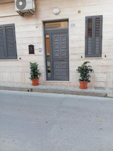 a house with two potted plants in front of a door at A Za' Nella Avola in Avola