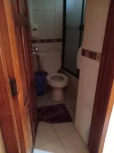 a small bathroom with a toilet and a door at Hostal Chimborazo in Corona