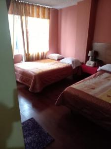 1 dormitorio con 2 camas y ventana en Hostal Chimborazo, en Corona