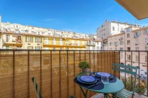 a table on a balcony with a view of buildings at Nice Renting - 9b Massena - Chic Escape in the Heart of Nice Comfort & Charm ! in Nice